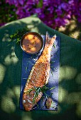 Fried red mullet with rosemary and sauce on a garden table