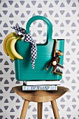 Turquoise shopping bag on stool decorated with banana & wooden monkey