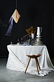 Stacked crockery, glasses and lit candles on table with white tablecloth