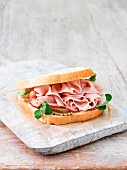 A ham sandwich with cucumbers, radishes and course mustard