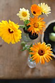 Yellow pot marigolds in glass vase on shabby-chic wooden table