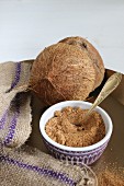 A bowl of coconut flower sugar with a halved coconut in the background