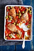 Oven-baked chicken drumsticks with peppers, onions and olives