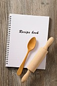 A recipe book, a wooden spoon and a rolling pin