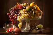 An autumnal fruit bowl featuring grapes, pears, persimmons and pomegranates