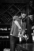 A sommelier opening a bottle of wine (black and white shot)