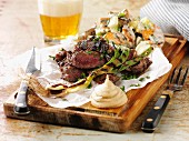 Grilled beef steak with spring onions and mustard on a chopping board