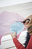 Mädchen schneidet Kreise nach Vorlage aus pastellfarbenem Seidenpapier aus