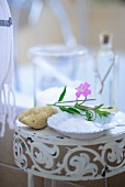 Bathing salts, a natural sponge and flowers on a side table in a bathroom