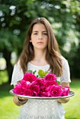 Girl holding tray of pink roses