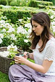 Girl cutting white roses in garden