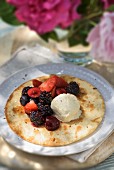 A pancake with berries and vanilla ice cream