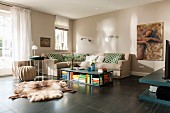 Comfortable lounge area with beige walls, corner sofa, coffee table and animal-skin rugs on dark floor