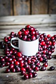 Cranberries in a mug and on a rustic wooden surface