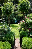 Sommerlicher, gepflegter Garten mit Rasenfläche und zwei Figuren
