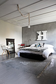 Felldecke auf Bett vor grauer Stuccolustrowand mit weißem Deko-Buchstabe, grauer Dielenboden und Teppichläufer