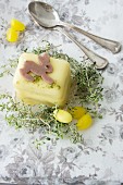 A petit four decorated with an Easter bunny, thyme and sugar eggs