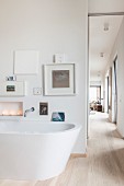 Free-standing bathtub below gallery of pictures and view into living room
