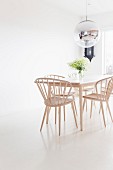 Helle Holzstühle um Tisch in skandinavischem Stil auf weißem Boden, oberhalb Kugelleuchte mit Spiegelung