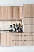 Einbauküche mit hellen Holzfronten, Espressomaschine, Kaffeemühle und Kaffeemaschine auf Küchenarbeitsplatte