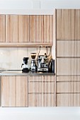 Fitted kitchen with pale wooden fronts, espresso machine, coffee mill and percolator on worksurface