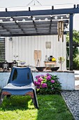 Shiny black plastic chair on lawn in front of hydrangea and pergola