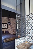 Ornamental wall-tiles in bathroom and view of double bed in bedroom