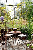 Filigrane Metallstühle um Vintage Tisch auf Natursteinboden in Orangerie mit nostalgischem Flair