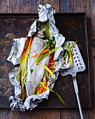 Trout with julienned vegetables in aluminium foil