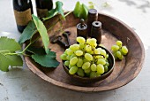 Green grapes with vine leaves and spices in a wooden dish (Italy)