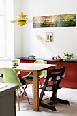 Green classic shell chairs and Tripp Trapp highchair around dining table below classic pendant lamp