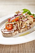An open summer sandwich with tuna fish, tomatoes and red onions