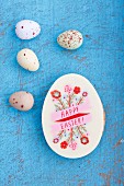 An egg-shaped Easter biscuit decorated with writing and sugar quail's eggs