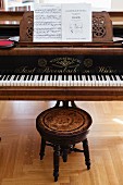 Music on stand of grand piano and antique stool with turned legs