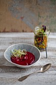 Creamy beetroot and coconut soup with onion sprouts and salad in a jar