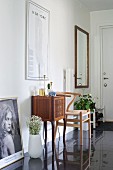 Antique cabinet and classic chair against wall of hallway with black glossy tiled floor