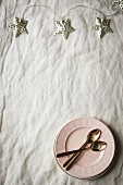 Star.shaped fairy lights, plates and spoon on fabric surface