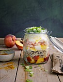 A layered salad with prawns, rice, peach and egg