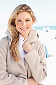 A young woman on a beach wearing a light fleece coat with a hood