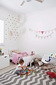 Bright girl's room with fabric pennant chain and playing girl on carpet