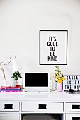 Black-framed saying above a desk with a laptop