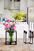 Bouquet in glass vase with metal frame and black metal candle holder