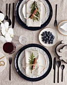Christmas place settings with patterned plate, black cutlery and cloth napkin; Blueberries and orchid