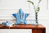 DIY-Dekostern mit Wolle in Blautönen umwickelt und mit Glasvase und Geschenken dekorativ arrangiert