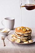 A stack of pancakes with bananas and maple syrup