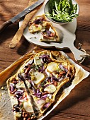 Tart flambée with pears, red onions, goat's cheese and Mediterranean herbs on a wooden table