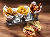 Three types of chips and a ham, cheese, tomato and lettuce sandwich on a rustic wooden table