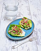 Avocado with bacon and radishes on lettuce leaves