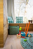 Holzverkleidete moderne Zimmerecke mit Eichenboden, Fenstersitzbank und Holzspielzeug