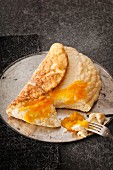 A sponge omelette on a round baking tray with pumpkin and orange marmalade, sliced